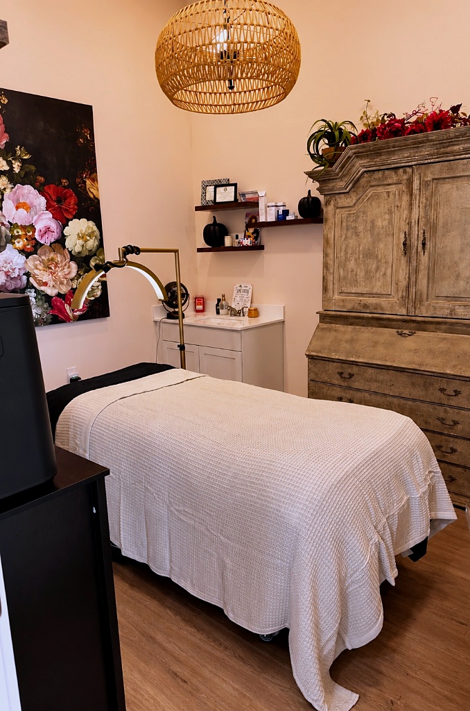 Kathleen Blecher's private treatment room inside Sweet Southern Blowouts in Weatherford, Texas, showing the treatment bed, floral artwork, vintage cabinet, and pendant light